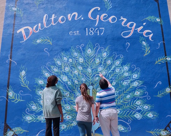 Students looking at a wall painting that says 