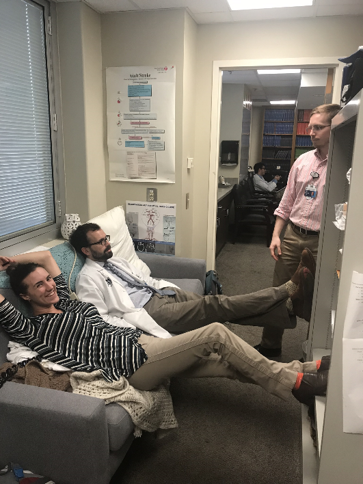 3 Residents in lounge taking a break, two sitting on a couch one standing.