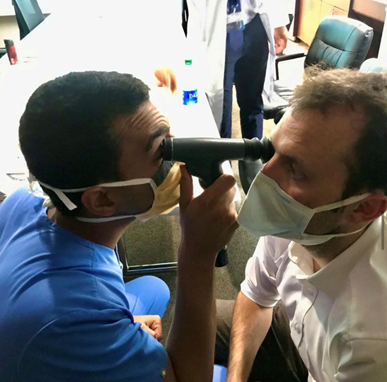Resident looking through an instrument at another person's eye.